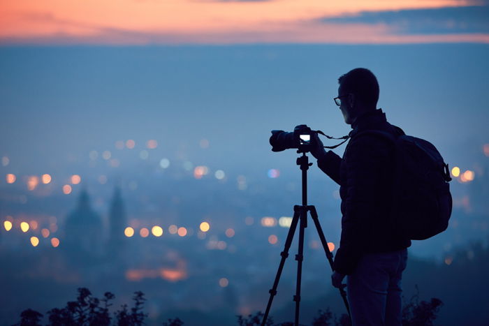 A photographer capturing a cityscape in the background A photographer capturing a cityscape in the background