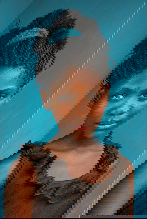 portrait of young girl in front of blue wall